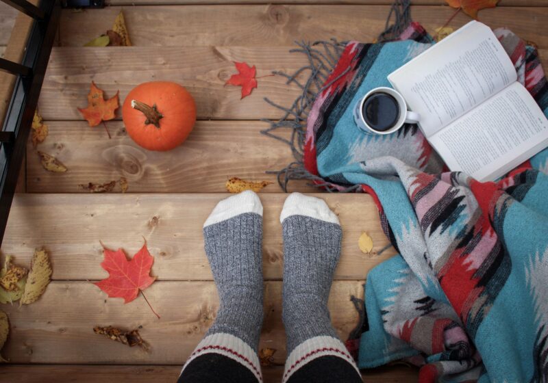 a girl reading a book and having coffee on a fall morning