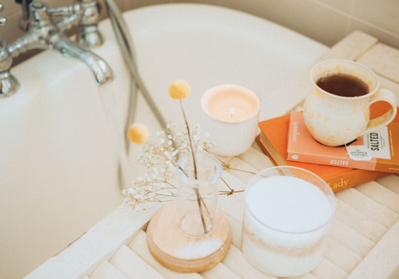 an image of self-care products like candles, bath salts, flowers, books