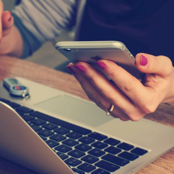 a woman using her phone while working on the laptop