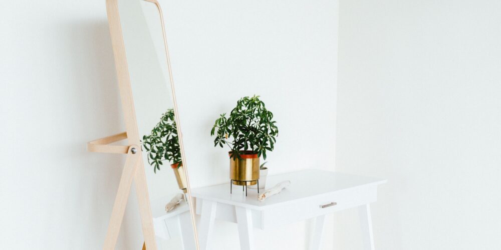 a minimalist setup with a standing mirror and a table with flowerpot