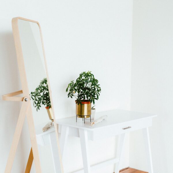 a minimalist setup with a standing mirror and a table with flowerpot