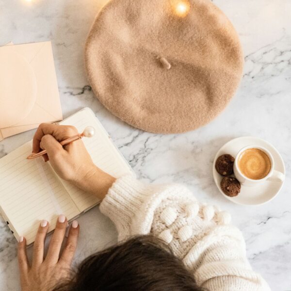 a girl writing in her journal while having coffee