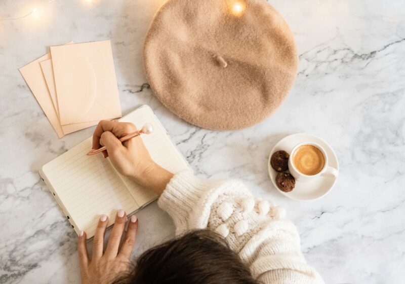 a girl writing in her journal while having coffee