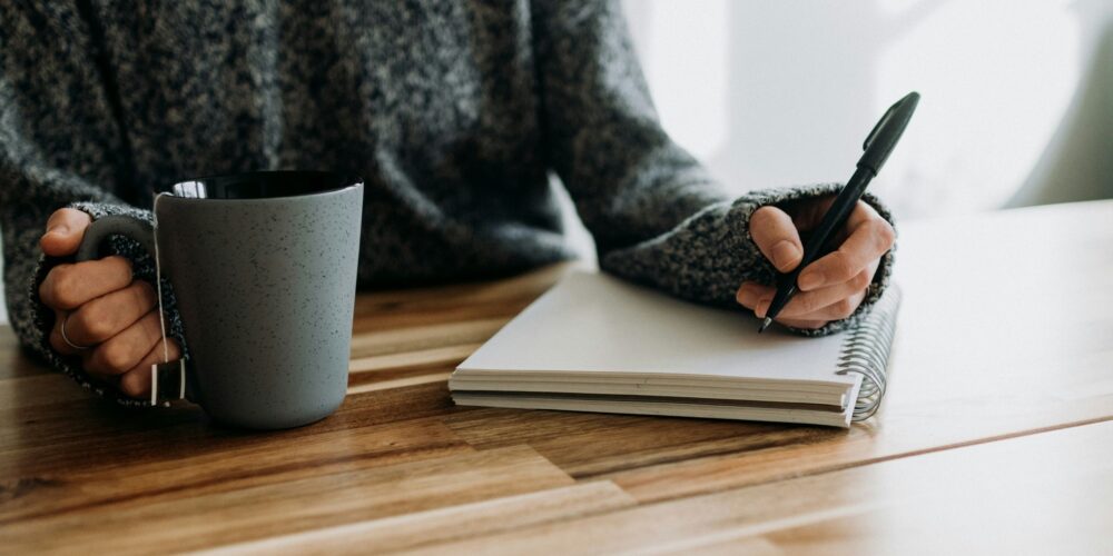 a girl writing in her journal while having coffee