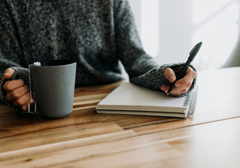 a girl writing in her journal while having coffee