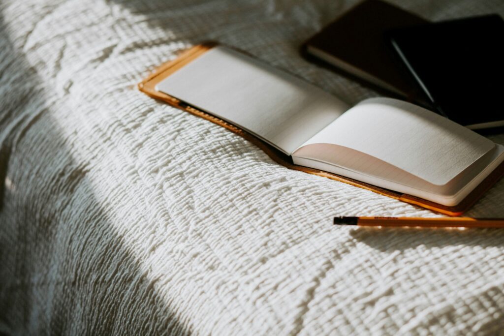 a journal with some pens on bed