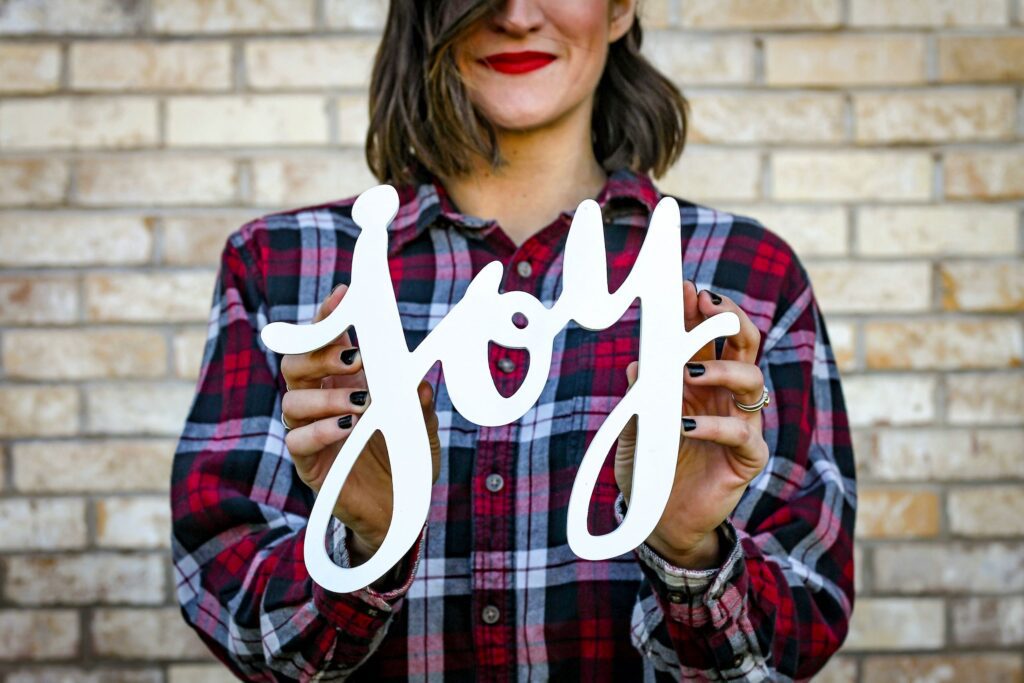 a girl living a happy life and holding a text that reads joy