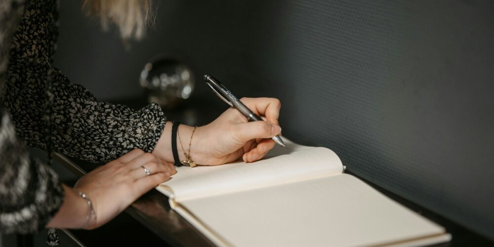 a woman writing on a diary journal with a pen