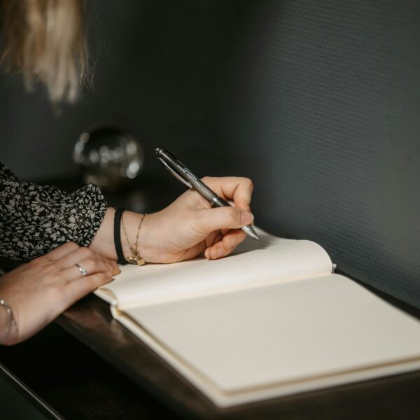 a woman writing on a diary journal with a pen