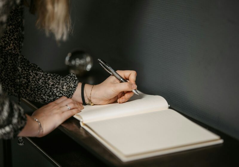 a woman writing on a diary journal with a pen