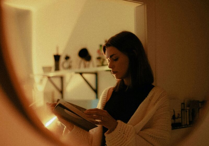 woman in white sweater holding her journal, weighing the pros and cons of journaling