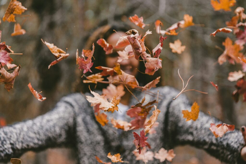 woman throwing maple leaves living a happy life