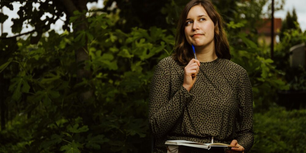 A girl sitting on a bench practicing self-care through journaling
