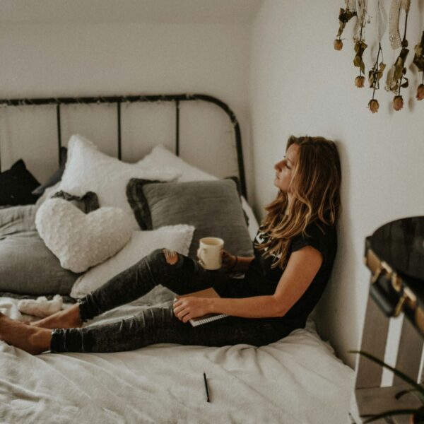 woman leaning on wall while sitting on bed wondering if journaling is a good form of therapy