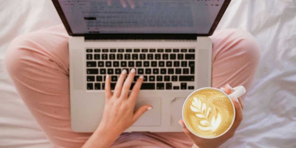 A woman working on her laptop with a notebook beside her, staying organized. Keeping a to-do list is a great way to manage tasks without feeling overwhelmed. It’s a small but effective self-care and work-life balance habit.