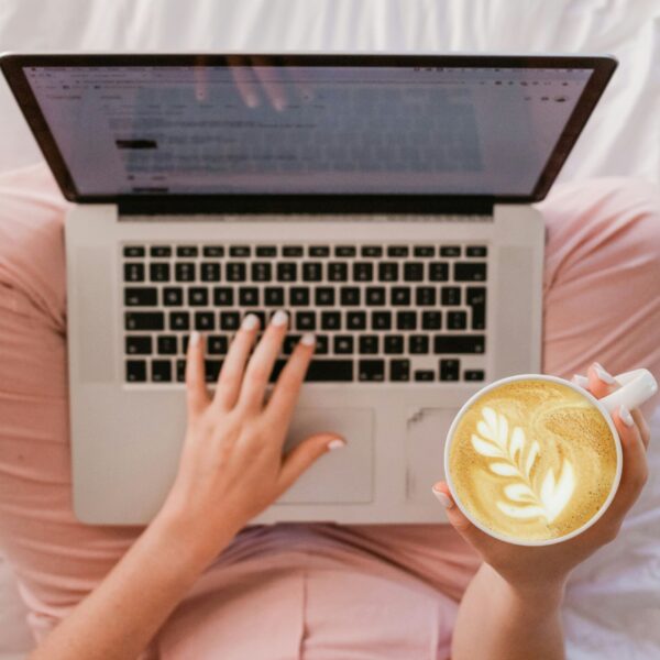 A woman working on her laptop with a notebook beside her, staying organized. Keeping a to-do list is a great way to manage tasks without feeling overwhelmed. It’s a small but effective self-care and work-life balance habit.