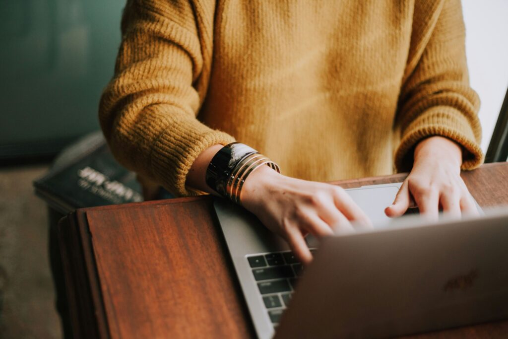  A woman working on her laptop in a clean, peaceful space. Keeping your workspace tidy and clutter-free is one of the easiest work-life balance examples to help reduce stress and improve focus.