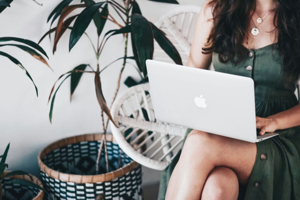 A woman sitting comfortably with her laptop, keeping good posture and looking relaxed. Simple things like sitting properly and stretching now and then are great workplace self-care examples for staying healthy at work.