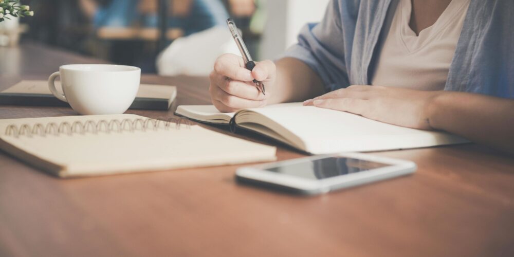 This image features a girl journaling at her study desk. A quiet space and a routine can make it easier to stay consistent with journaling and turn it into a daily habit.