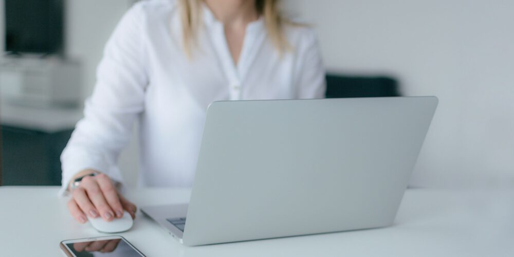 A professional woman is working on her laptop with a relaxed and focused expression. This image reflects the benefits of mindfulness in the workplace, such as better concentration and productivity.