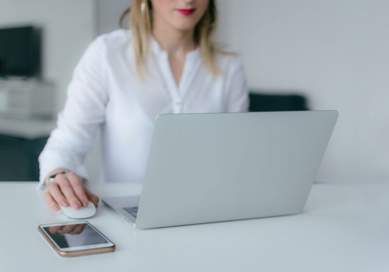 A professional woman is working on her laptop with a relaxed and focused expression. This image reflects the benefits of mindfulness in the workplace, such as better concentration and productivity.