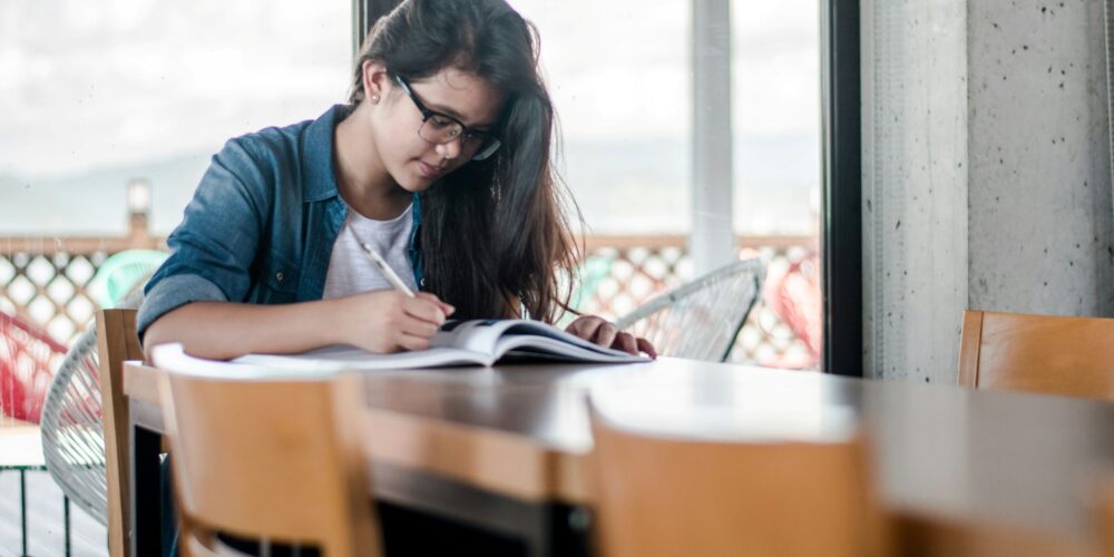 A close-up of a person writing in a journal with a cup of coffee nearby, symbolizing the practice of journaling for memory improvement and self-reflection.