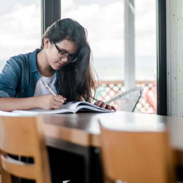 A close-up of a person writing in a journal with a cup of coffee nearby, symbolizing the practice of journaling for memory improvement and self-reflection.