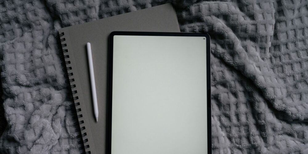 This image shows a cozy journal and an iPad placed on a bed, creating a relaxing setup for journaling before bed