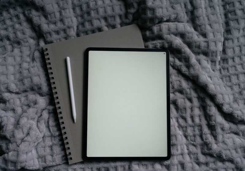 This image shows a cozy journal and an iPad placed on a bed, creating a relaxing setup for journaling before bed