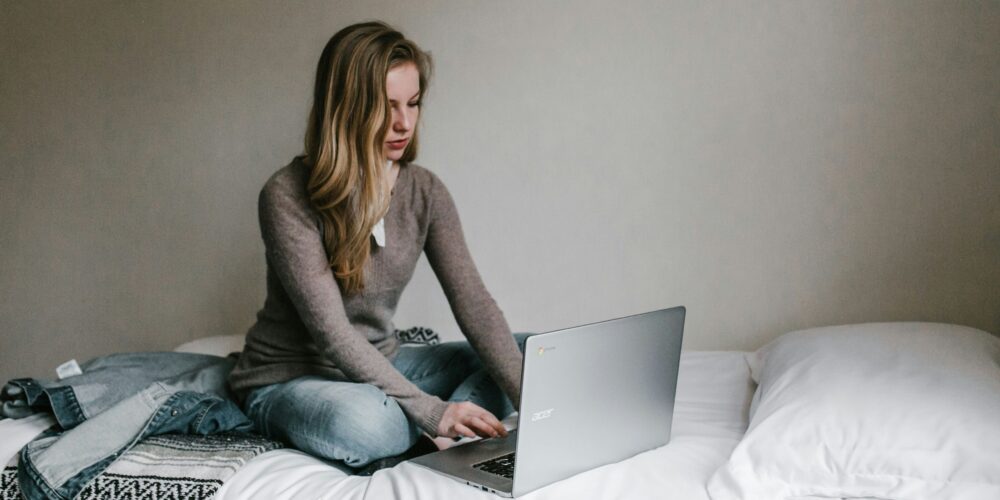 A girl working on her laptop from bed, illustrating a relaxed yet productive mindful morning routine for working professionals.