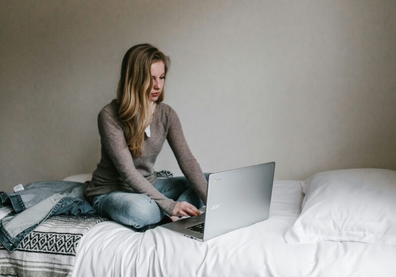 A girl working on her laptop from bed, illustrating a relaxed yet productive mindful morning routine for working professionals.