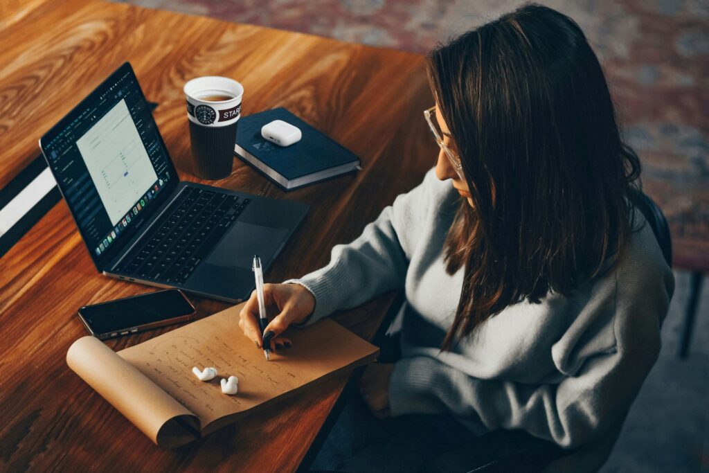 This image captures a moment of quiet journaling at a desk—one of the simplest stress management techniques for professionals using journaling for work stress relief.