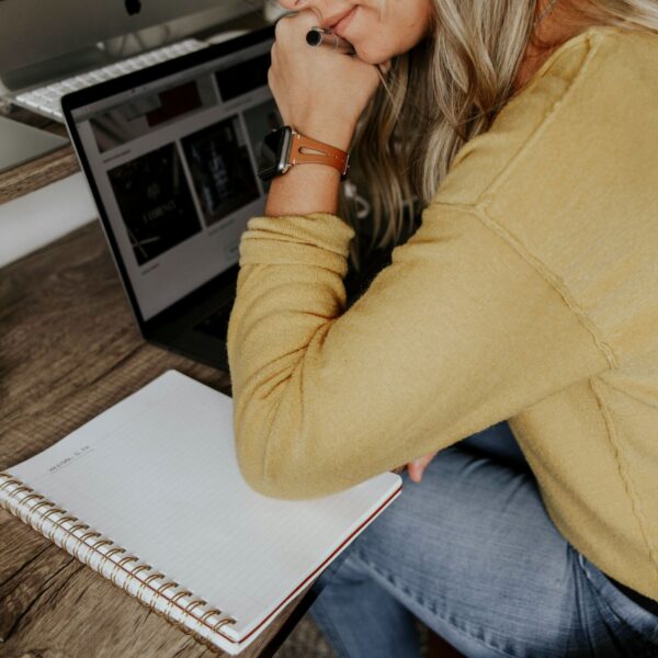 This image shows a woman writing in a notebook at her work desk, reflecting the idea of practicing mindfulness at work through journaling to reduce stress and stay grounded.