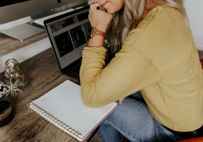 This image shows a woman writing in a notebook at her work desk, reflecting the idea of practicing mindfulness at work through journaling to reduce stress and stay grounded.