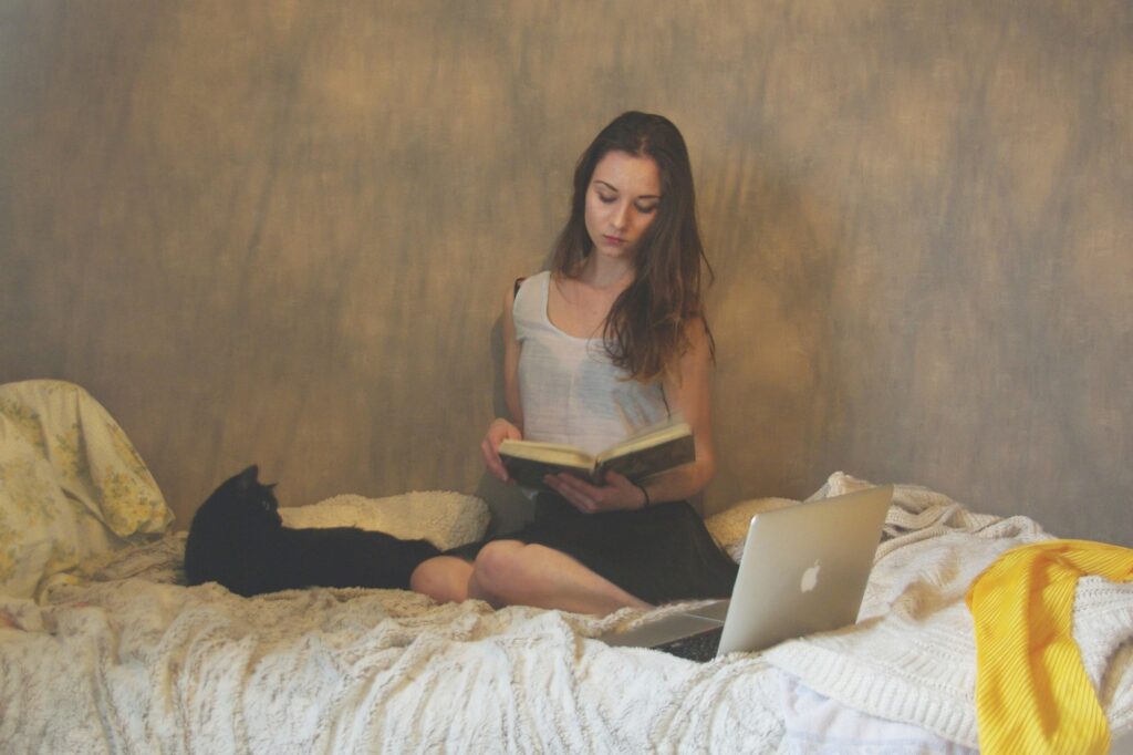 This image features a woman writing in her journal while sitting on a bed, practicing her nighttime journaling routine.