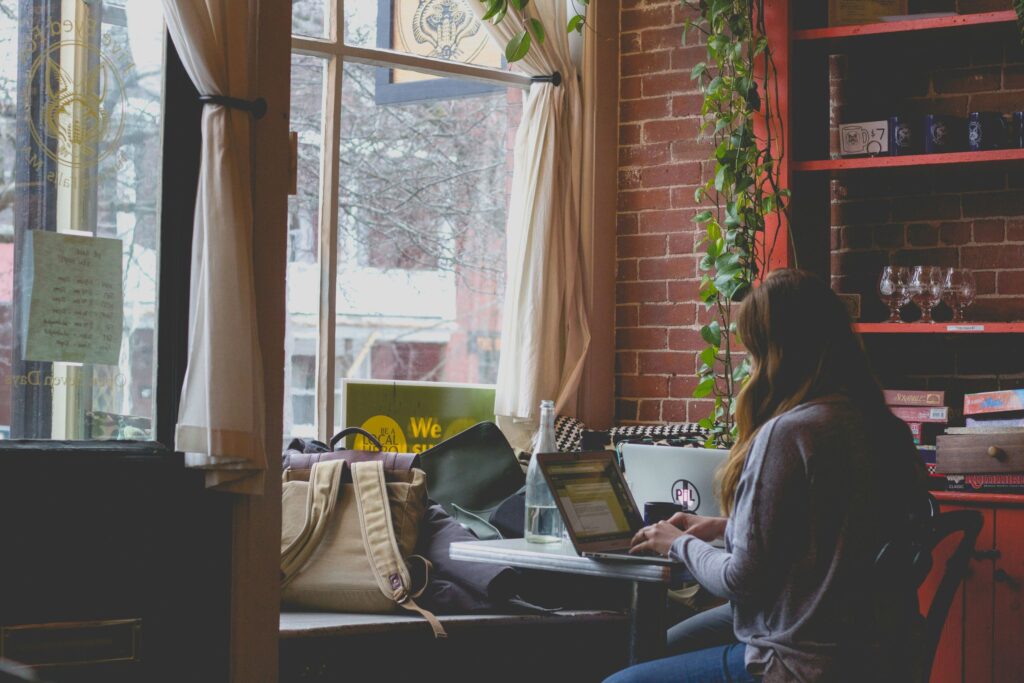 A woman working on her laptop in a peaceful environment, representing the balance many seek between productivity and personal well-being. It reflects the ongoing struggle with perfectionism and work life balance in modern professional life.
