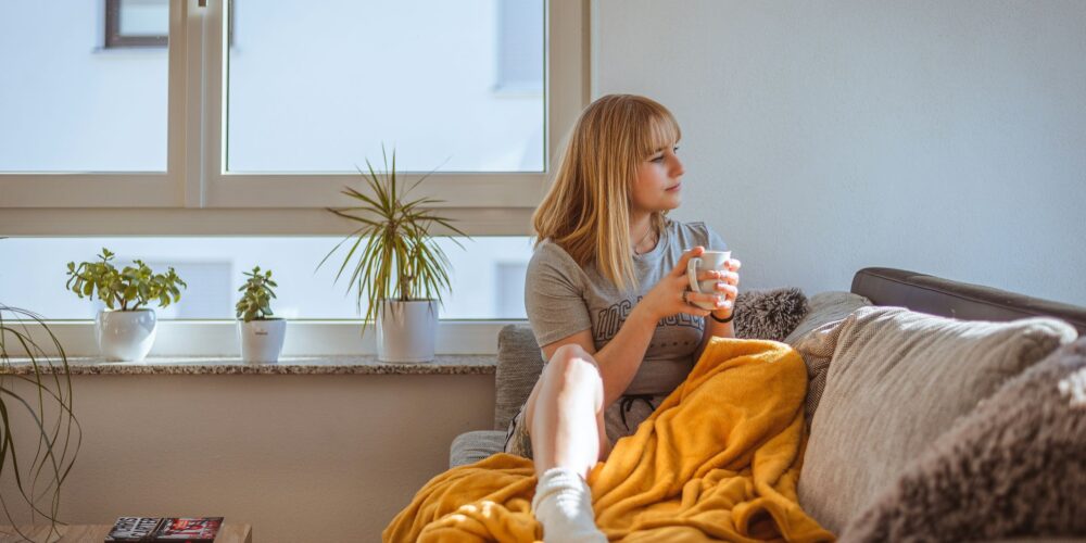 A woman sitting peacefully on a couch, enjoying her coffee after a long and stressful workday