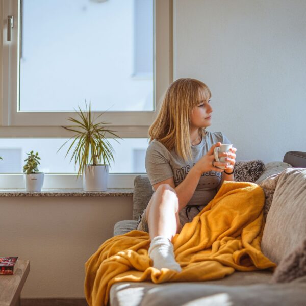 A woman sitting peacefully on a couch, enjoying her coffee after a long and stressful workday