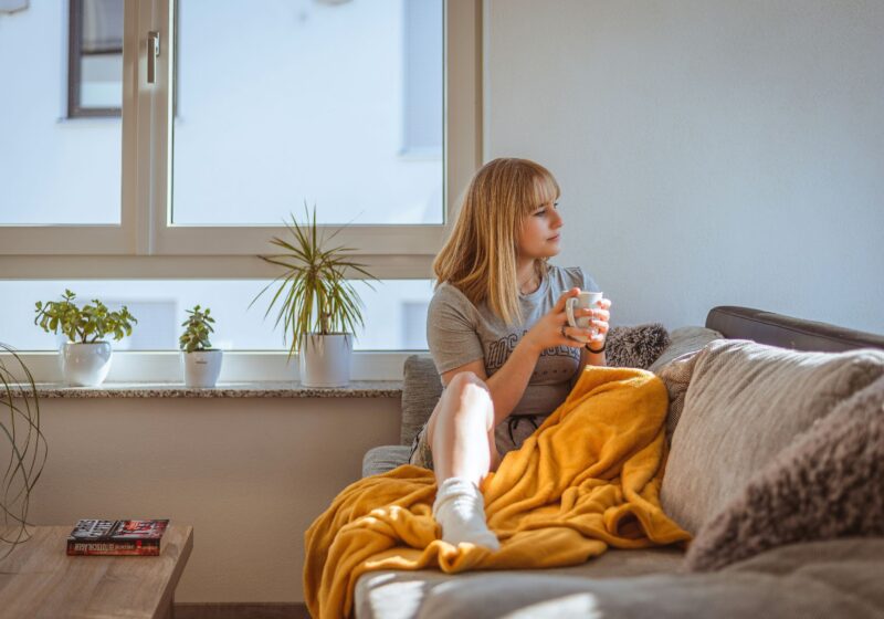 A woman sitting peacefully on a couch, enjoying her coffee after a long and stressful workday
